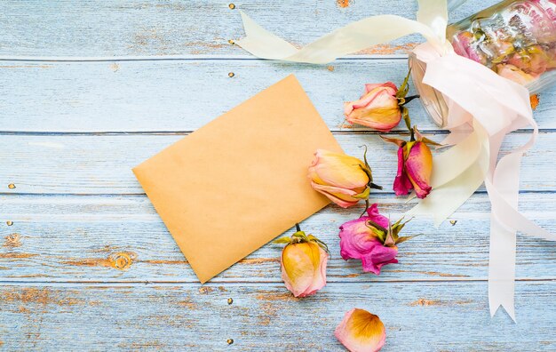 Sobre vacío sobre un fondo de madera rodeado de flores rosas