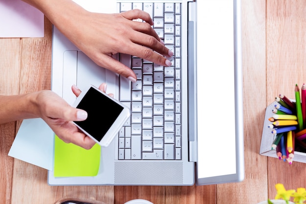 Sobrecarga de manos femeninas usando la computadora portátil y el teléfono inteligente