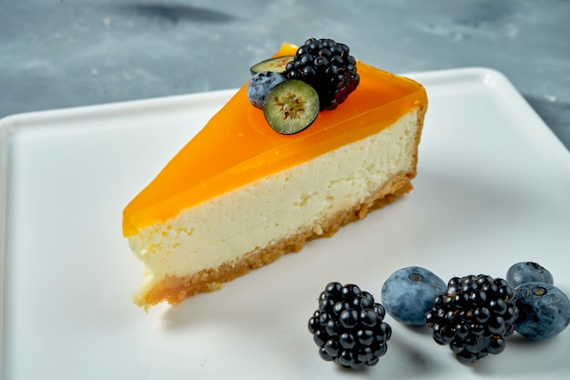 Sobremesa apetitosa - cheesecake com caramelo e frutas vermelhas em um prato branco. Massa saborosa