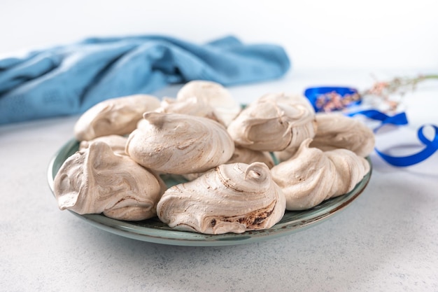 Sobremesa caseira de merengue de ovo em uma placa de cerâmica sobre fundo claro na parte de trás é azul