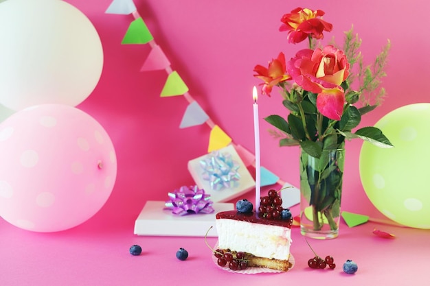 Sobremesa com creme branco decorado com frutas frescas e uma vela acesa, rosas frescas, balões