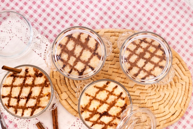 Sobremesa de arroz doce tradicional portuguesa sobre uma mesa com paus de canela.