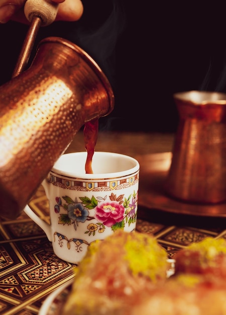 Sobremesa de baklava de pistache em um café oriental quente de fundo escuro em cezve