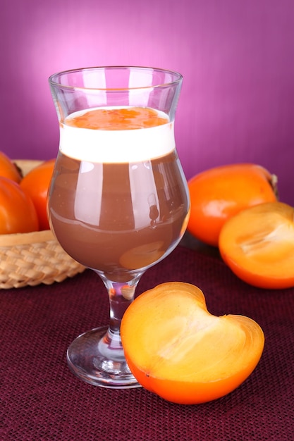 Sobremesa de chocolate e caqui na mesa no fundo roxo