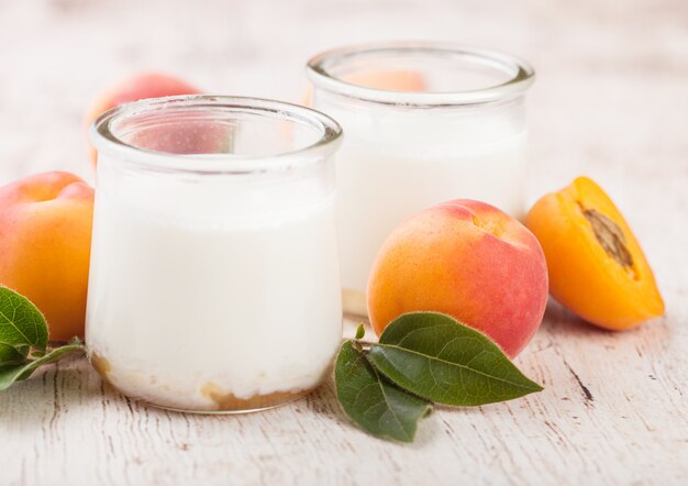 Sobremesa de creme fresca com os damascos orgânicos crus na placa de madeira.