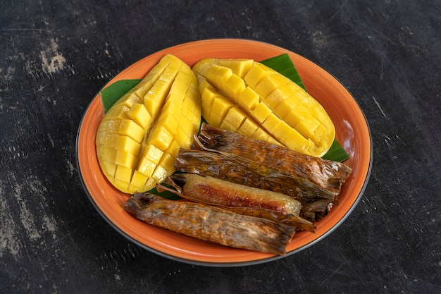 Sobremesa de estilo tailandês, manga amarela com arroz pegajoso de banana em folhas de palmeira. Manga amarela e arroz pegajoso são alimentos tradicionais populares da Tailândia. Fechar-se