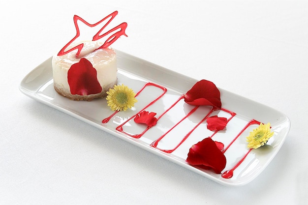 Sobremesa de panna cotta guarnecida com caramelo e pétalas de rosa, comida em fundo branco