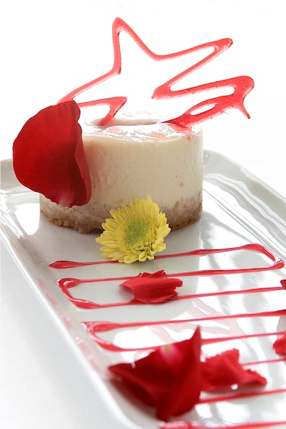 Sobremesa de panna cotta guarnecida com caramelo e pétalas de rosa, comida em fundo branco