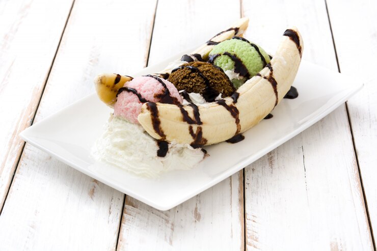 Foto sobremesa de sorvete de banana com calda de chocolate no fundo branco de madeira