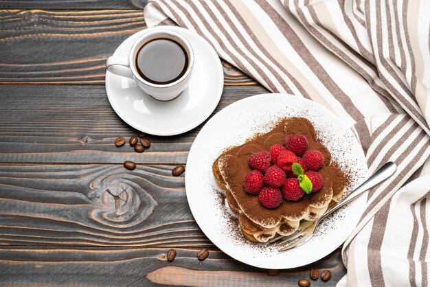 Sobremesa de tiramisu clássico com framboesas e uma xícara de café expresso