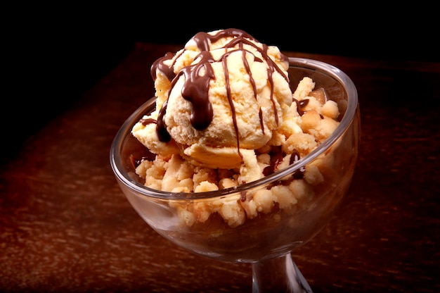 Sobremesa de xícara de sorvete com torta de maçã e molho de chocolate closeup na mesa de madeira