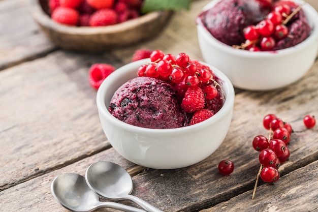 Sobremesa deliciosa e romântica. Uma bola de morsa framboesa caseira com frutas frescas em um copo branco sobre um fundo de madeira. Fechar-se