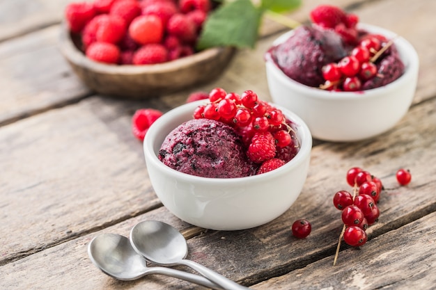 Sobremesa deliciosa e romântica. Uma bola de morsa framboesa caseira com frutas frescas em um copo branco sobre um fundo de madeira. Fechar-se