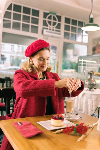 Sobremesa e café. Mulher francesa elegante sentada em uma padaria agradável, servindo sobremesa e café