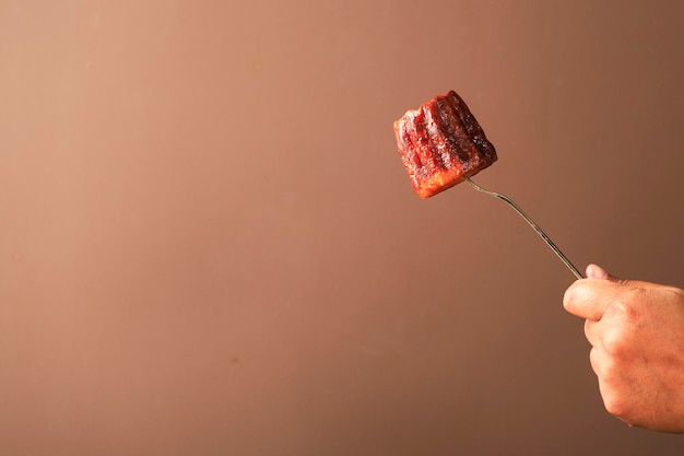 Sobremesa francesa de bolo de Cannele no garfo, mão feminina segurando o garfo com Canelle caramelizado, espaço de cópia