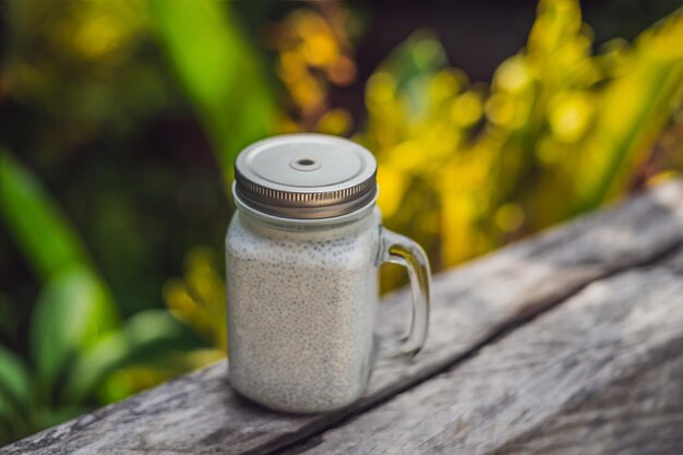 Sobremesa saudável em camadas com pudim de chia em um frasco de pedreiro em fundo rústico.