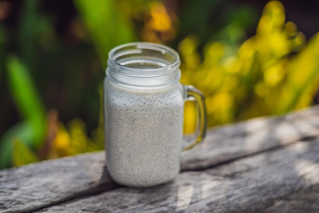 Sobremesa saudável em camadas com pudim de chia em um frasco de pedreiro em fundo rústico.