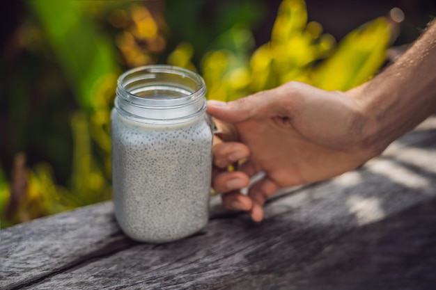 Sobremesa saudável em camadas com pudim de chia em um frasco de pedreiro em fundo rústico.