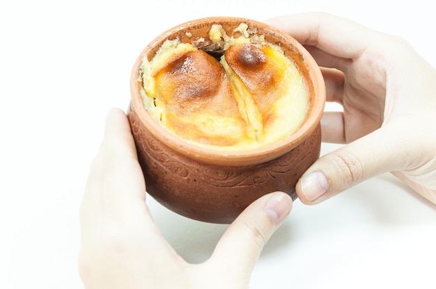 Sobremesa tailandesa em potes de barro na mão femininaMung Bean Thai Custard Dessert em fundo branco estilo de comida tailandesa