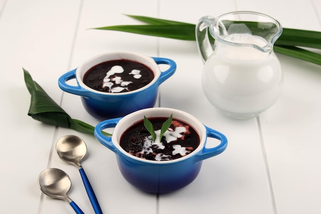 Sobremesa Tradicional Indonésia: Bubur Ketan Hitam ou Mingau de Arroz Glutinoso Preto, Servido com Molho de Leite de Coco e Guarnecido com Folhas de Pandan. Two Bowl, Fundo Branco, Close Up