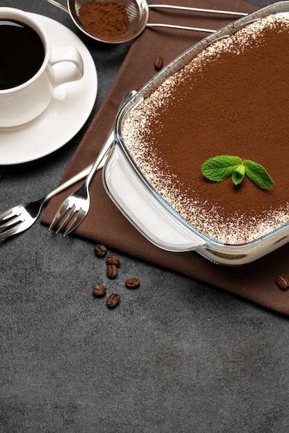 Sobremesa tradicional italiana tiramisu em assadeira de vidro e xícara de café expresso quente fresco