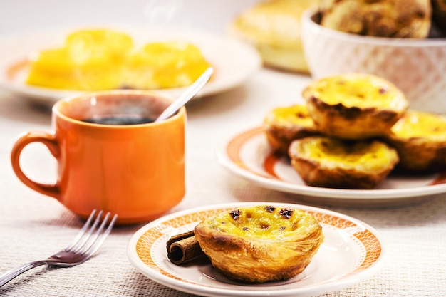 Sobremesa tradicional portuguesa de pastel de nata e bree de lis e pão ao fundo servido com café doces típicos de Lisboa