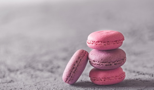 Foto sobremesas deliciosas coloridas bonitas makarons, pilha na pedra cinzenta.