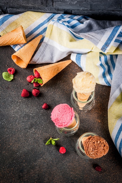 Sobremesas doces de verão e sobremesas, vários tipos de sorvete em cones rosa (framboesa), baunilha e chocolate com menta no escuro