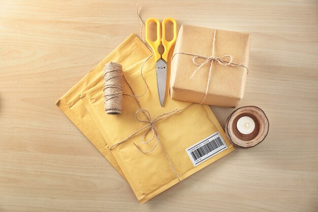 Sobres acolchados y caja de regalo de paquete en mesa de madera