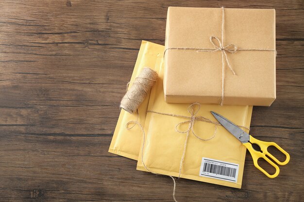 Sobres acolchados y caja de regalo de paquete en mesa de madera