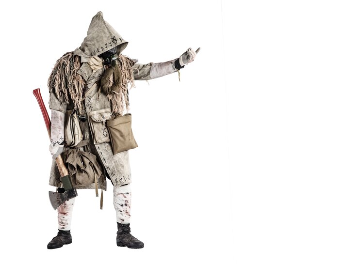 Foto sobrevivente do mundo pós-apocalipse, bandido ou saqueador com máscara de gás, capa ghillie, roupas esfarrapadas com runas, mostrando um sinal acenando enquanto está de pé com o machado de carpinteiro na mão, isolado no broto branco