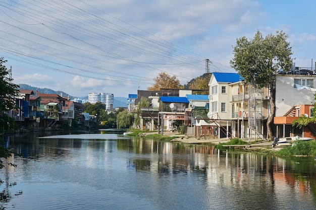 Sochy, Rusia - 14 de septiembre de 2020: la orilla del río Dagomys está completamente construida con pequeñas cabañas con garajes para botes, edificios de gran altura y montañas en el horizonte