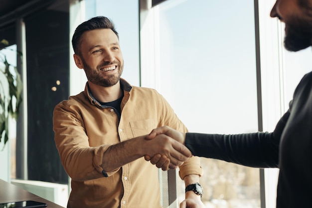 Sociedad de negocios empresarios masculinos sonrientes dándose la mano celebrando el acuerdo de cooperación en