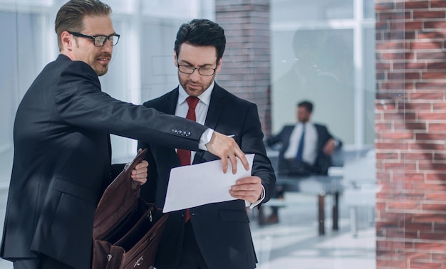 Los socios comerciales discuten el documento que se encuentra en el lobby de la oficina el concepto de relación comercial