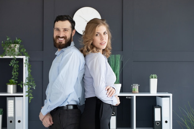 Foto socios comerciales exitosos con un hombre y una mujer jóvenes posando espalda con espalda.