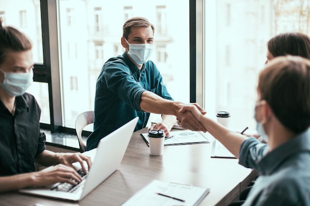 socios comerciales en máscaras protectoras dándose la mano.