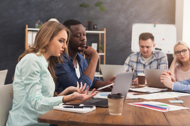 Socios comerciales serios que trabajan en la oficina moderna. Dos compañeros de trabajo discutiendo un nuevo proyecto mientras trabaja en la computadora portátil, espacio de copia