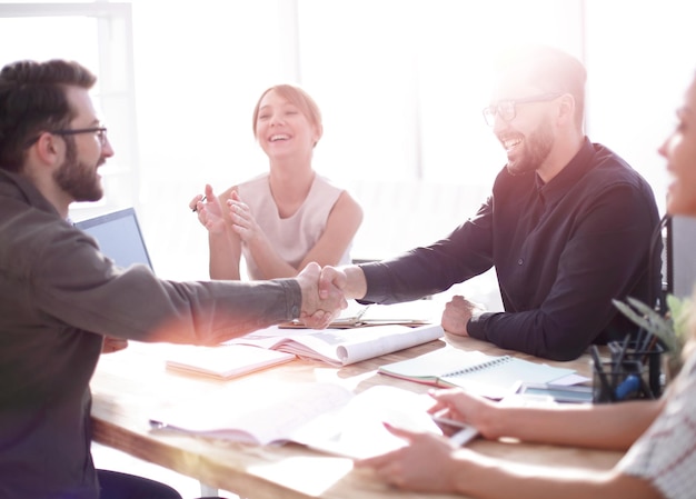 Socios comerciales sonrientes dándose la mano en una reunión de negocios