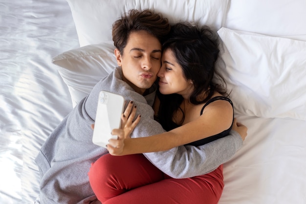 Foto socios tomando selfie en la cama endecha plana