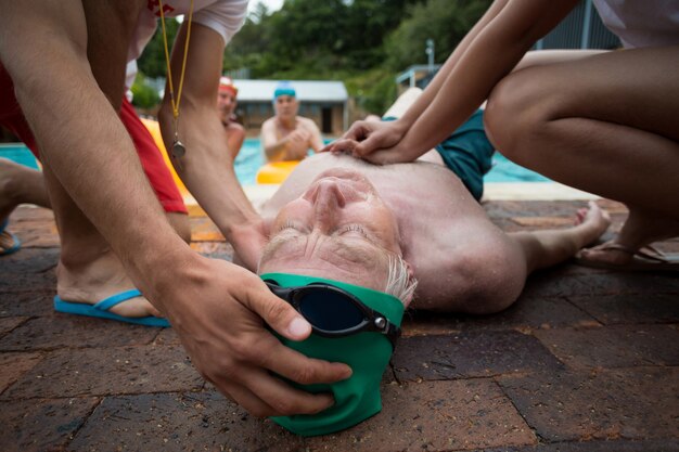 Socorristas presionando el pecho del hombre mayor inconsciente junto a la piscina