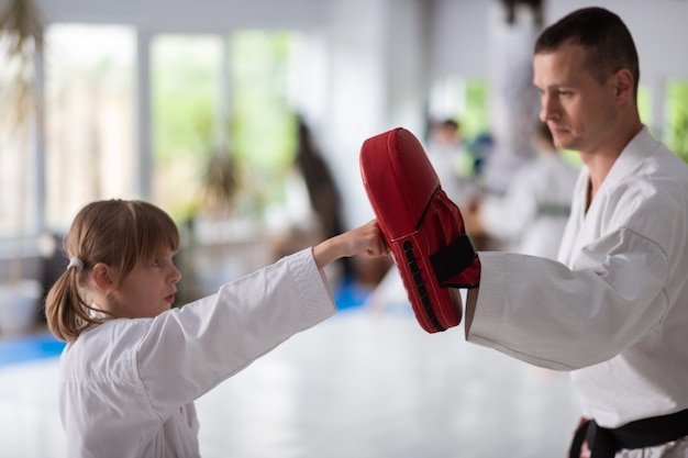 Socos com o treinador. linda garota atraente que adora artes marciais praticando socos com o treinador