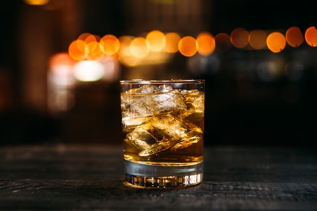 Soda Whisky Cocktail mit Eiswürfeln in der alten Mode Glas auf dem Holztisch mit verschwommenen Bokeh Lichter Hintergrund