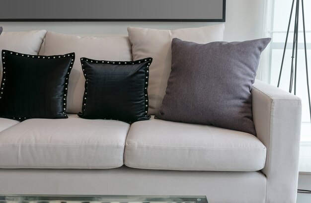 Sofá blanco con almohadas negras y grises en el interior de la sala de estar