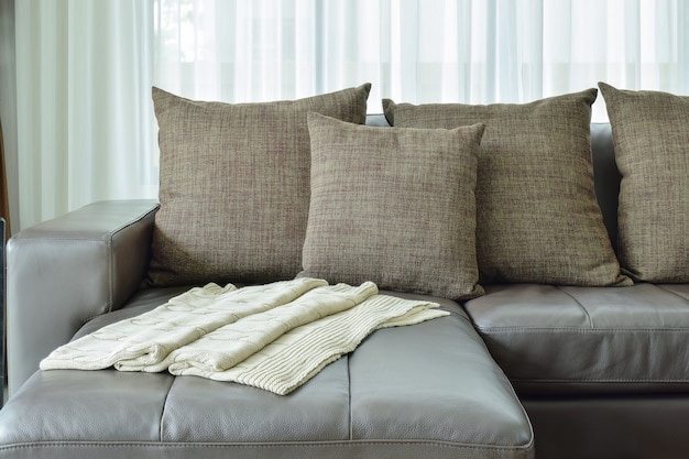Sofá de cuero gris con textura marrón almohadas en sala de estar moderna