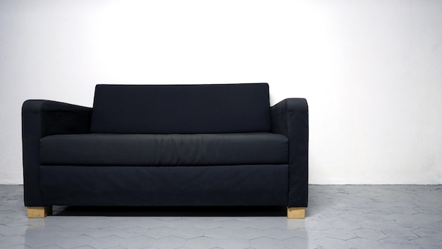 Sofá de cor preta feito de madeira e tecido na sala branca e piso cinza e sem pessoas