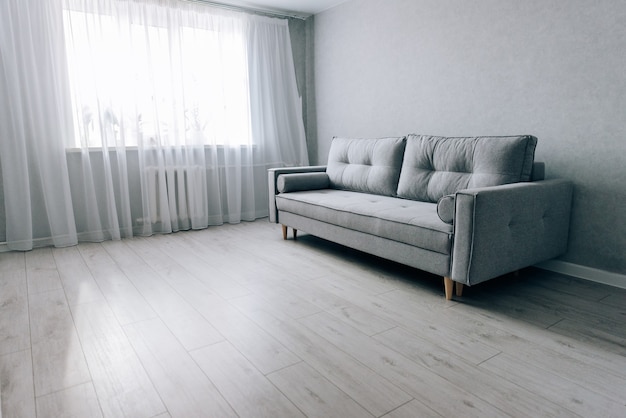 Sofá gris moderno con patas de madera en la habitación.