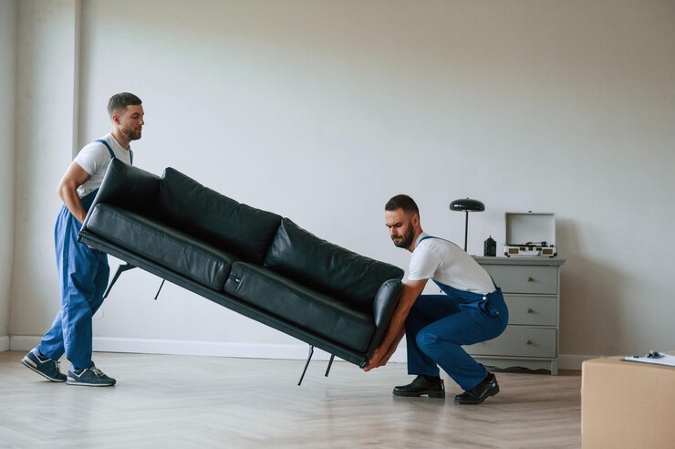 Foto sofa nas mãos dois funcionários do serviço de mudança num quarto