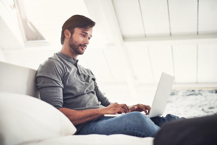 Foto sofa relaxante e homem digitando em laptop para pesquisa rede e projeto freelance on-line em casa site trabalho remoto e designer no sofá com computador para streaming de e-mail ou escrever artigo