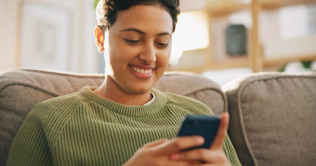 sofá de la sala de estar smartphone scroll o persona leyendo artículo de blog o comunicación manos de teléfono en el hogar o mujer feliz relajarse sonreír y escribir búsqueda en línea experiencia del cliente revisión y comprobación de la aplicación