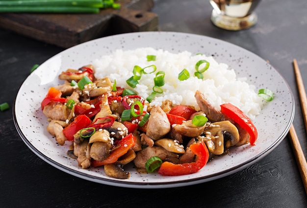 Sofreír con pollo, champiñones, pimientos dulces y arroz hervido. Comida china.